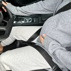 Pregnant woman driving a car while using a pregnancy seat belt adjuster that positions the lap belt safely under the belly.